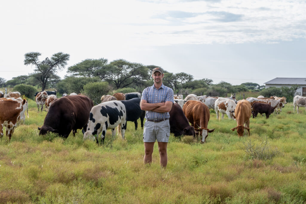 Farmer standing in front of a herd of cattle.